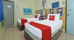 Un dormitorio con dos camas con sábanas rojas y blancas. en SPOT ON 90625 Super Green Grass Hotel, en Yong Peng