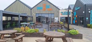 Un patio con mesas y mesas frente a un edificio. en Heavenly Huts GC056, en Saint Osyth