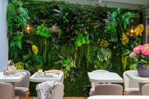 a wall covered in plants and flowers with tables and chairs at Hotel Daumesnil-Vincennes in Vincennes
