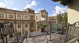a balcony with two benches and a table and buildings at Marroad Inn Tokyo in Fuchu