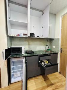 Una cocina con gabinetes blancos y una encimera negra. en Ghar - near expo mart -cozy stay away from home, en Greater Noida