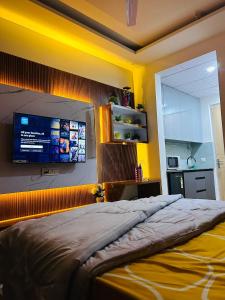 1 dormitorio con 1 cama grande y TV en la pared en Ghar - near expo mart -cozy stay away from home, en Greater Noida