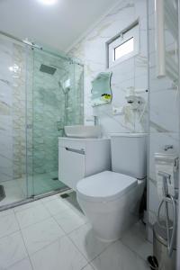 a white bathroom with a toilet and a shower at Hotel Harmony Premium in Kutaisi