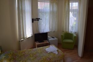 a bedroom with a bed and a chair and a television at Hotel Tintyava 2 in Varshets