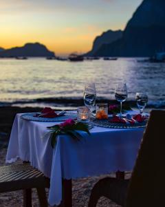 a table with wine glasses on the beach at Cadlao Resort and Restaurant in El Nido +273 photos