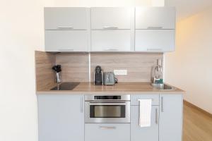 eine weiße Küche mit weißen Schränken und einer Spüle in der Unterkunft Beau studio rénové, balcon, accès plage, piscine in Biarritz + 4 Fotos