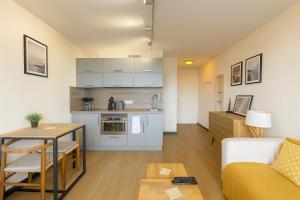 eine Küche und ein Wohnzimmer mit einem Sofa und einem Tisch in der Unterkunft Beau studio rénové, balcon, accès plage, piscine in Biarritz