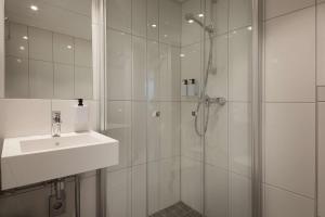 a white bathroom with a shower and a sink at Scandic Victoria Lillehammer in Lillehammer +38 photos