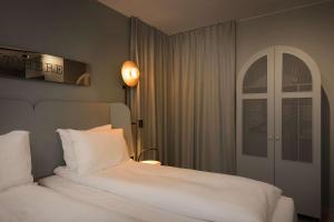 a bedroom with a white bed and an arched window at Scandic Victoria Lillehammer in Lillehammer
