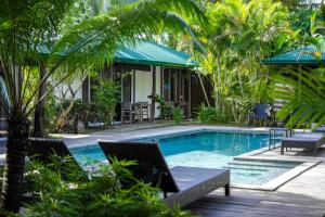 a swimming pool in a resort with chairs and trees at Cadlao Resort and Restaurant in El Nido