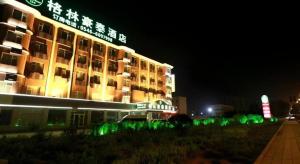a building with green lights in front of it at night at GreenTree Inn Dongying Xisi Road Huachuang Building in Kenli