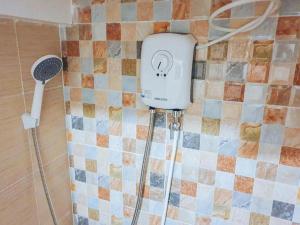 ein Bad mit einem Duschkopf an einer gefliesten Wand in der Unterkunft RedDoorz near SGM Condotel Villa Beach Iloilo in Molo + 44 Fotos
