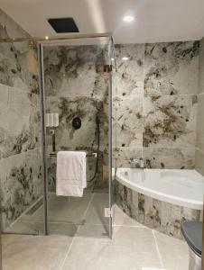 a bathroom with a shower and a tub and a sink at Hotel Srimanta sankardev in Majuli