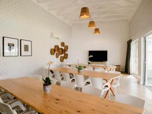 a dining room with wooden tables and white chairs at Bateleur Guesthouse in Klerksdorp