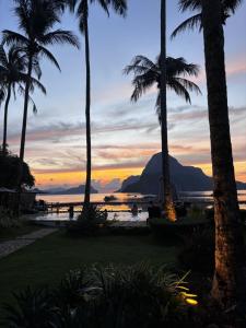 a sunset at the beach with palm trees at Cadlao Resort and Restaurant in El Nido