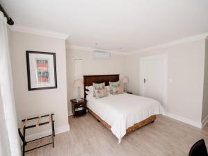 a bedroom with a white bed with a wooden headboard at Bateleur Guesthouse in Klerksdorp +13 photos