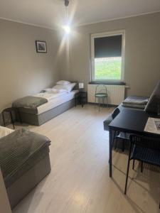 een kamer met twee bedden, een tafel en een raam bij Hotelik nad jeziorem w Łasinie in Łasin