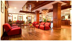 a lobby with red chairs and tables and a chandelier at Royal Crown Hotel & Spa in Siem Reap