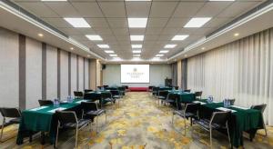a conference room with green tables and chairs and a screen at Jinjiang Metropolo Hotel Shenyang Country Garden Datong Lake Subway Station Branch in Shenyang