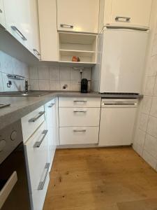 a white kitchen with white cabinets and a wooden floor at Savognin Rundigna in Savognin +3 photos