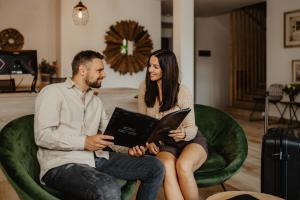 a man and woman sitting in a green chair with a laptop at Hotel Frýdl in Prague