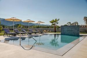 a swimming pool with chairs and umbrellas at Villa La Caretta in Alikanas