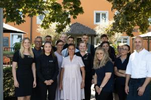 un groupe de personnes posant une photo devant une maison dans l'établissement Ganter Hotel & Restaurant Mohren, à Île de Reichenau