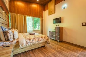 ein Schlafzimmer mit einem Bett und einem Fernseher darin in der Unterkunft Amara Woods Villa in Rāipur