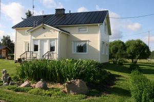 a small white house with a black roof at Puskan Mummola in Pello