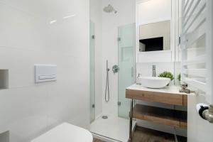 a white bathroom with a sink and a shower at Schoeps Residence Stylowe Apartamenty Blisko Starego Rynku by Noclegi Renters in Poznań