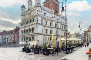 a building with tables and umbrellas in front of it at Schoeps Residence Stylowe Apartamenty Blisko Starego Rynku by Noclegi Renters in Poznań