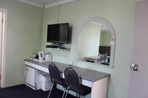 a room with a desk with two chairs and a mirror at High Mountains Motor Inn in Blackheath