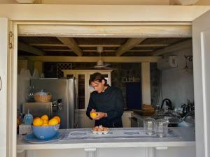 a woman standing in a kitchen holding an orange at Halgoduria in Santa Marina Salina