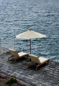 two chairs and an umbrella next to the water at Halgoduria in Santa Marina Salina