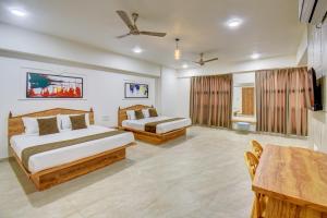 una habitación de hotel con dos camas y una mesa en Hotel Majestic Pearl, en Nashik
