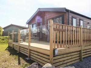 a house with a deck with a sign on it at Curlew Lodge in Carnforth