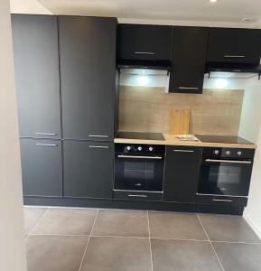 a kitchen with black cabinets and a stove at ღ Ordemique - Coeur de ville 7 chambres, Wifi fibre in Douai +16 photos