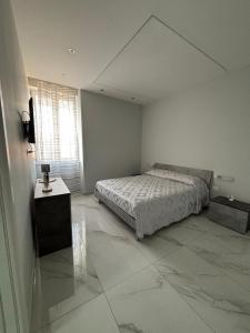 a white bedroom with a bed and a window at La casa dei sogni in Torre del Greco