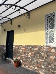 a yellow building with a black door and a brick wall at La casa dei sogni in Torre del Greco