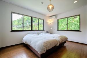 a bedroom with a large bed and two windows at BROOK COTTAGE MINAKAMI in Minakami