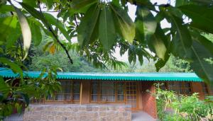 a house with a blue roof and a brick building at Sparrow Woods Eco Resort in Nainital