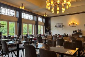 a dining room with tables and chairs and windows at Amrâth Hotel DuCasque in Maastricht