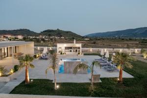 an outdoor swimming pool with palm trees and lounge chairs at Villa La Caretta in Alikanas