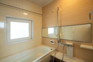 ein Badezimmer mit Badewanne und Fenster in der Unterkunft Muku House Urayasu in Tokio