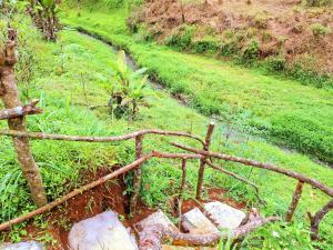 ein verrosteter Zaun auf einem Feld neben einigen Felsen in der Unterkunft Ciwidey Jungle Camp & Cabin in Gambung + 4 Fotos