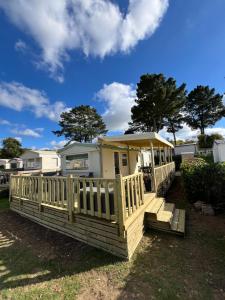 a house with a wooden deck with a gazebo at Mobil home 3 chambres 5 personnes Finistère in Clohars-Carnoët
