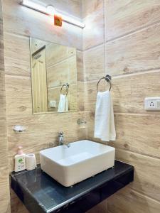 a bathroom with a white sink and a mirror at The Kufri Mansion I Three-Bedroom Villa l by Exotic Stays in Kūfrī