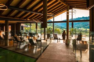 une pièce avec des chaises et des tables et une grande fenêtre dans l'établissement La Roccia Wellness Hotel, à Cavalese