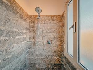 y baño con ducha y pared de azulejos. en Appartamento Il Piano - HelloElba, en Rio Marina