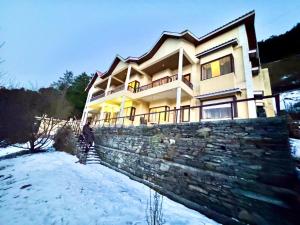 a man standing in front of a house in the snow at Boutique Hotels & 3 Bed Rooms Villas I Vacations I Conference I MICE I Family Events I Open Air Terrace I Sky Bonfire I Charvi Retreat by Exotic Stays in Kūfrī